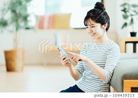 リビングでスマホを操作する若い女性。 109439313