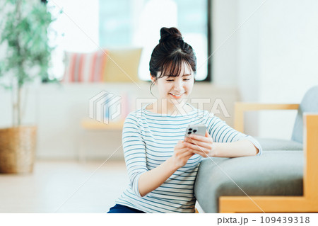 リビングでスマホを操作する若い女性。 109439318