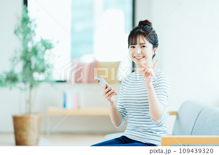 リビングでスマホを操作する若い女性。 リビングでスマホを操作する若い女性。 109439320