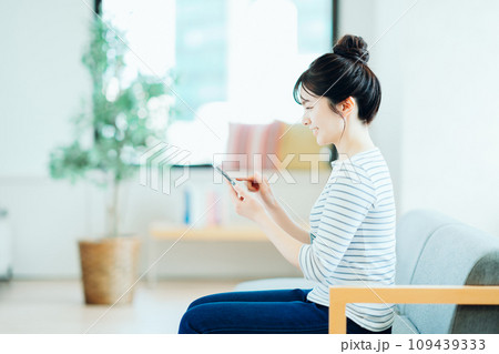 リビングでスマホを操作する若い女性。 リビングでスマホを操作する若い女性。 109439333