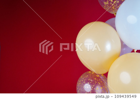 Light balloons - white, beige, transparent, pearl on a red background. Horizontal photo. Space for text 109439549
