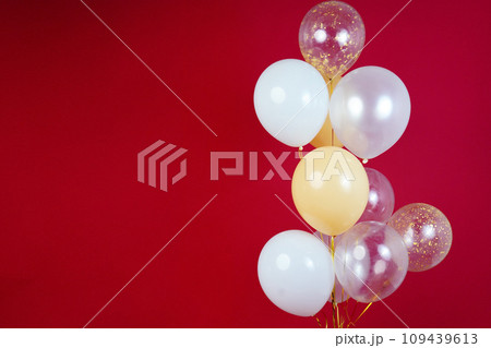 Light balloons - white, beige, transparent, pearl on a red background. Horizontal photo. Space for text 109439613