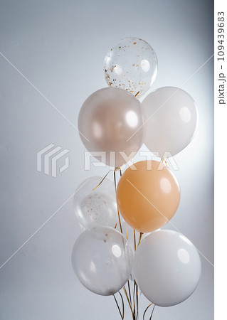 Balloons in white, beige and transparent colors on a gray background. 109439683