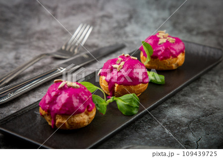 dessert of baked buns with raspberry topping and seed decorations, side view 109439725