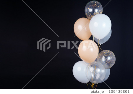 A bunch of balloons in white, beige and transparent colors on a dark background with space for an inscription A bunch of balloons in white, beige and transparent colors on a dark background with space for an inscription 109439801