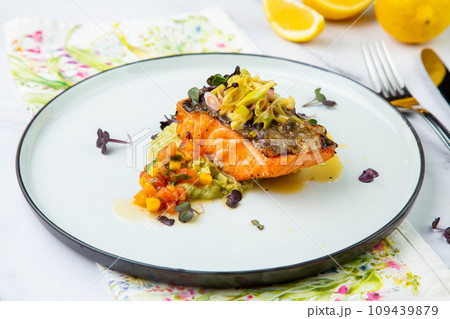 red fish with vegetable sauce and puree on a round plate side view 109439879