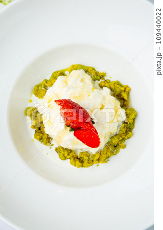 curd dessert with strawberries on top in a white plate on a marble background, top view 109440022