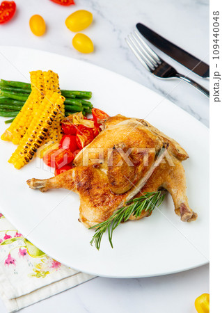 chicken thighs with corn, cherry tomatoes and herbs side view 109440048