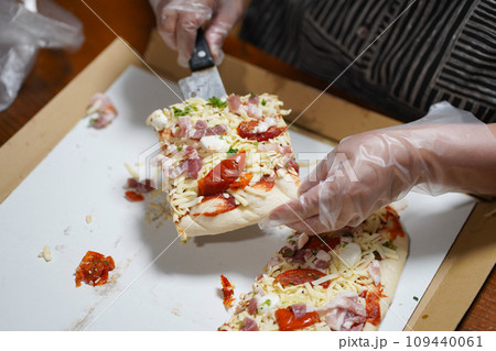 ピザを切り分けて保存する女性 109440061