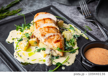 side view of chicken breast in cheese sauce with herbs on a black tray side view of chicken breast in cheese sauce with herbs on a black tray 109440136