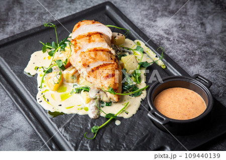 side view of chicken breast in cheese sauce with herbs on a black tray side view of chicken breast in cheese sauce with herbs on a black tray 109440139