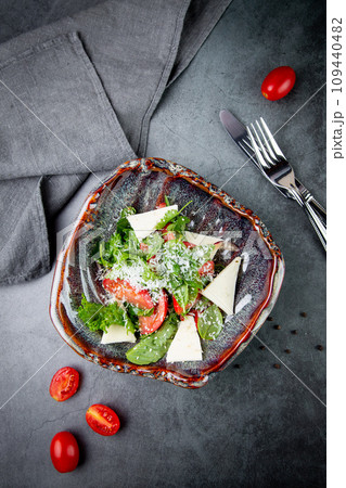 salad with herbs, tomatoes, grated cheese, sesame seeds and pieces of cheese, top view 109440482
