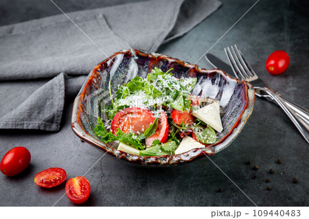 salad with herbs, tomatoes, grated cheese, sesame seeds and pieces of cheese, top view 109440483