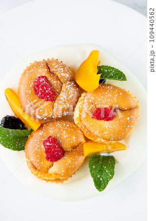 muffins with peach, raspberry, black berry and mint covered with powdered sugar, side view muffins with peach, raspberry, black berry and mint covered with powdered sugar, side view 109440562