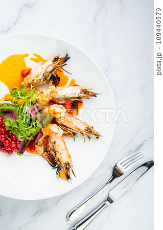 cooked shrimp with herbs and berries on a white plate, side view 109440579