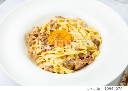 pasta in cream sauce with egg and black pepper on top side view pasta in cream sauce with egg and black pepper on top side view 109440704