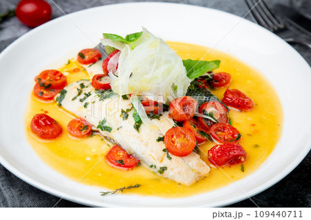 unpeeled fish with gravy, herbs, cherry tomatoes and onions, top view 109440711