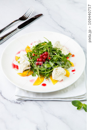 arugula salad with peach slices and red berries on a white plate top view 109440757