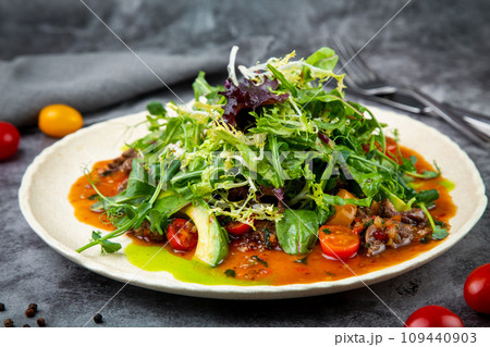 meat gravy with meat, cherry tomatoes and a bunch of greens on top, side view 109440903