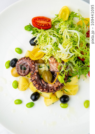 salad with olives, herbs, cherry tomatoes, potatoes and octopus tentacles top view 109441095