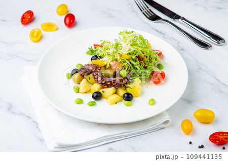 salad with olives, herbs, cherry tomatoes, potatoes and octopus tentacles side view salad with olives, herbs, cherry tomatoes, potatoes and octopus tentacles side view 109441135