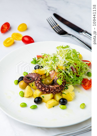 salad with olives, herbs, cherry tomatoes, potatoes and octopus tentacles side view salad with olives, herbs, cherry tomatoes, potatoes and octopus tentacles side view 109441138