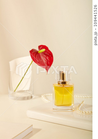 Perfume product branding ideas with mockups for design. On a white background, glass bottle unbranded decorated with pearl necklace, vase of flower and notebook. Front view 109441526