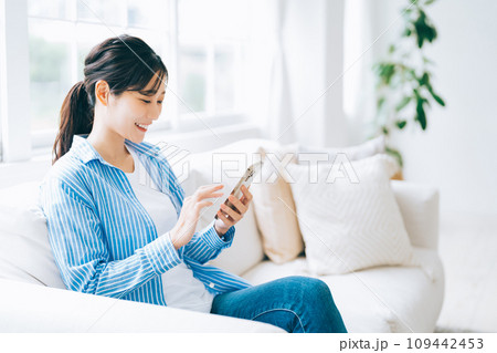 ソファに座ってスマホを操作する女性 109442453