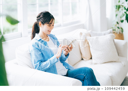ソファに座ってスマホを操作する女性 ソファに座ってスマホを操作する女性 109442459