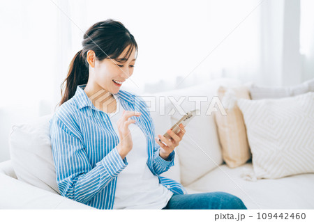 ソファに座ってスマホを操作する女性 ソファに座ってスマホを操作する女性 109442460