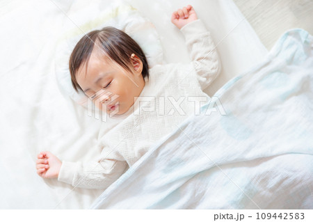 部屋で眠る1歳児　お昼寝　バンザイ寝 109442583