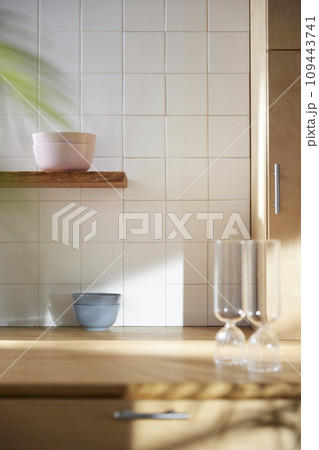 A sunny kitchen with white tile walls, a wooden table and sink. A sunny kitchen with white tile walls, a wooden table and sink. 109443741