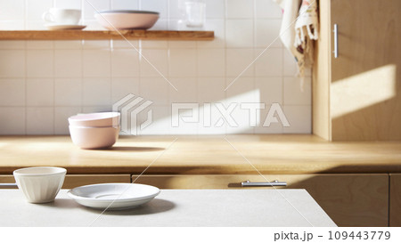 A sunny kitchen with white tile walls, a wooden table and sink. 109443779