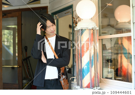 理容室の前で悩むアジア人の男性の理容師 理容室の前で悩むアジア人の男性の理容師 109444601