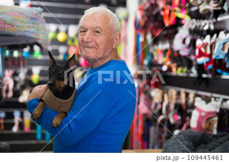 Portrait of elderly man with his dog in winter clothes visiting pet supplies shop Portrait of elderly man with his dog in winter clothes visiting pet supplies shop 109445461