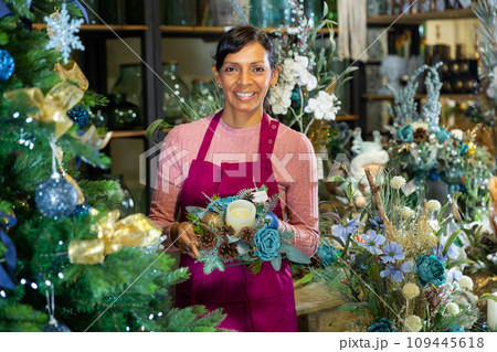 Portrait of a woman seller holding a Christmas composition with candles 109445618