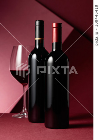 Glass and bottles of red wine on a red background. 109446419