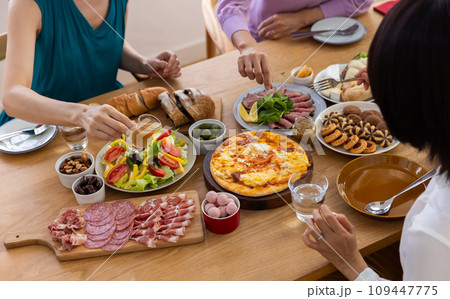 テーブルに並んだ料理を食べる女性 109447775