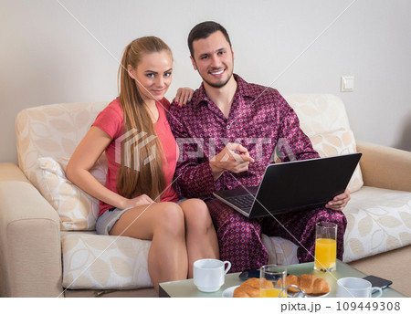 Cute young couple having breakfast, in front of laptop computer 109449308