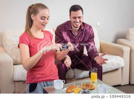 Cute young couple having breakfast, photographs at mobile phone 109449316