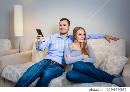 Portrait of couple sitting on sofa watching television. 109449345