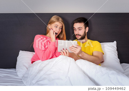 Young Sweet Couple at Bed Watching Something on Tablet Gadget 109449462
