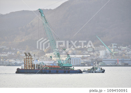 冬の北海道函館市函館港で現場に向かうクレーン台船と引き船の風景を撮影 109450091