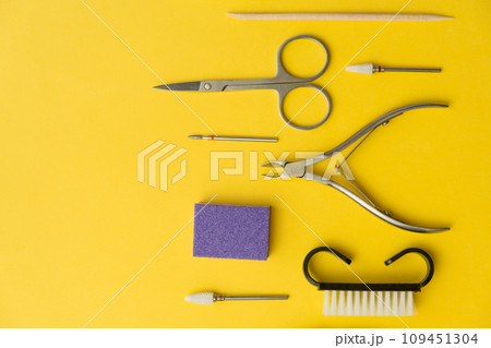 Professional manicure tools on yellow background. Manicure set. Top view. Cuticle pusher, cuticle trimmer and purpose scissor. Set of manicure and pedicure tools and cosmetics with space 109451304