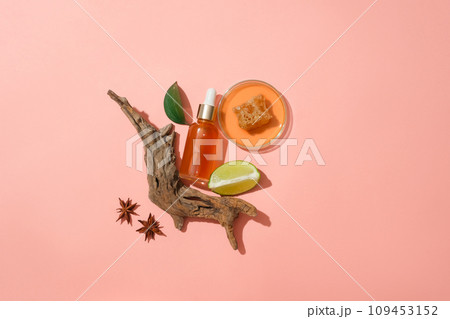 Honey and beeswax contained inside a petri dish. Unlabeled bottle displayed with tree branch and lime. Skin care concept with empty label Honey and beeswax contained inside a petri dish. Unlabeled bottle displayed with tree branch and lime. Skin care concept with empty label 109453152