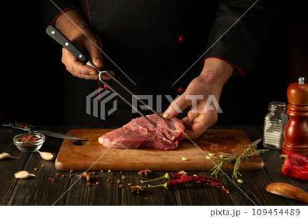 The process of preparing a meat steak by the hands of a chef on a kitchen table with aromatic spices. Cooking juicy and flavorful shish kebab for lunch or dinner 109454489