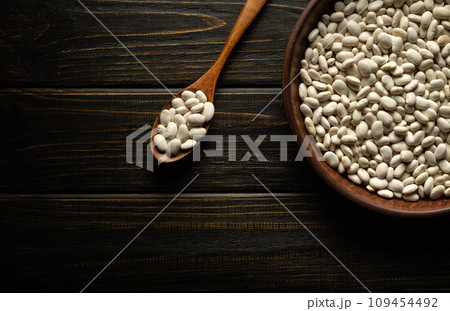 White raw bean grains in a plate and vintage spoon before preparing a delicious dish. Diet food concept with beans 109454492