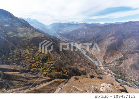 Ravine, winding river, and towering snow-capped mountain peaks. Natural background. 109457115
