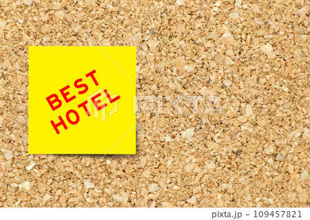 Yellow note paper with word best hotel on cork board background with copy space 109457821