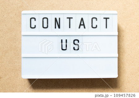 Lightbox with word contact us on wood background 109457826